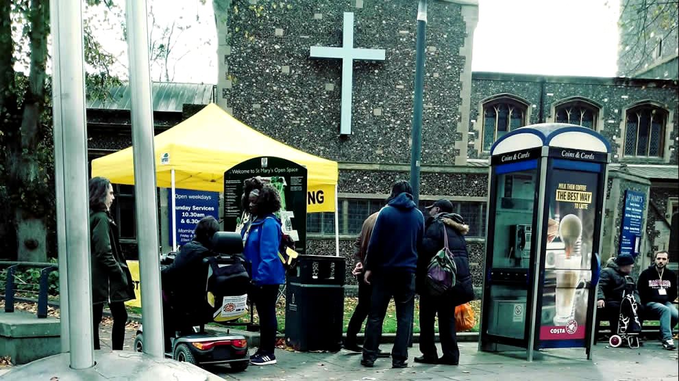 The Church Without Walls team with their yellow gazebo outside St Mary&rsquo;s Church on Watford High Street, talking and praying with people passing by