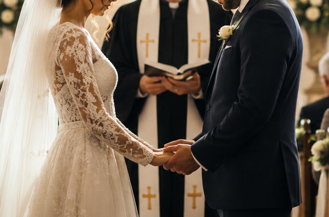 A bride and groom joining hands as they make their vows during a wedding service